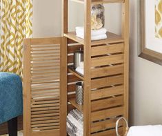 a wooden shelf with towels and other items on it next to a blue chair in a living room