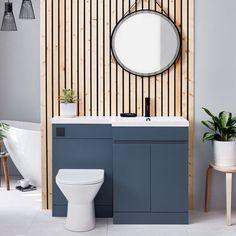 a white toilet sitting next to a sink under a round mirror on a wooden wall