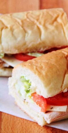 two sub sandwiches sitting on top of white paper