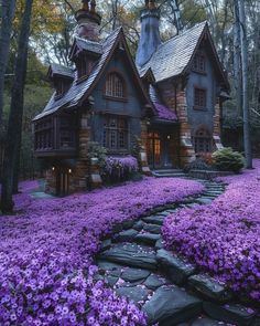 a house surrounded by purple flowers in the woods