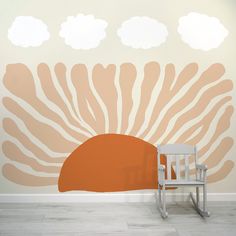 a white rocking chair sitting in front of a wall painted with an orange sun and clouds