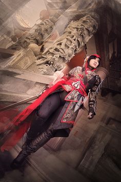 a woman dressed in red and black standing next to a statue