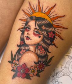 a woman's leg with flowers and sun tattoo on it