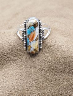 "Stunning Ladies Spiny Oyster and Turquoise Combination Sterling Silver Ring Top is 25x15mm.   7/8 x 7/16 inches Weight:  5.7 grams US Size: 10-1/2.  Can be re-sized for no additional cost. 925 Silver, Handmade $75 Exclusively Designed by Richard James for Richlo Jewelry Check out our other fine jewelry at:  https://etsy.com/shop/arizonagemstudio In life, Spiny Oyster shells had some very imposing \"quills\" which could be used for camouflage or protection from other species. Interestingly, I am told that those who tend to keep others at a distance or hold their emotions very close to the vest would benefit from this softened version of the Spiny Oyster Shell which may help them to become more approachable, if even just a little. Literally, helping them to come out of their shell.  Turquoi Multicolor Natural Stone Turquoise Ring In Sterling Silver, Multicolor Natural Stones Turquoise Ring In Sterling Silver, Multicolor Turquoise Ring With Natural Stones In Sterling Silver, Unique Multi-stone Turquoise Ring In Sterling Silver, Multicolor Artisan Turquoise Ring In Sterling Silver, Multicolor Artisan Turquoise Sterling Silver Ring, Multicolor Turquoise Artisan Ring In Sterling Silver, Adjustable Silver Turquoise Multi-stone Ring, Sterling Silver Multi-stone Turquoise Ring Gift