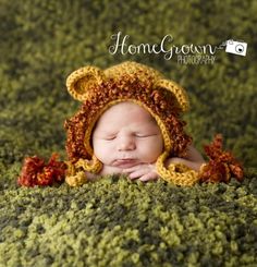 a baby wearing a crocheted bear hat laying on top of a green blanket