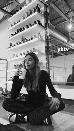 a woman sitting on the floor drinking from a cup