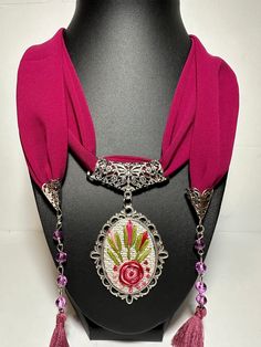 Step into a world of artisanal beauty with this 100% Handmade Embroidered Necklace, featuring a stunning stainless silver-plated chain that enhances the elegance of this wearable work of art. 🌟 Key Features 🌟 ✨ Unparalleled Craftsmanship: Each necklace is lovingly handcrafted, ensuring that every piece is a unique and exquisite creation. Women's scarf necklace features on soft infinity loop scarf with jewelry and accessory. ✨ Intricate Embroidery: The pendant boasts intricate, detailed embroidery, a testament to our commitment to creating wearable masterpieces. ✨ Versatile Beauty: Perfect for everyday wear or special occasions, this necklace infuses your style with timeless grace. ✨ Customizable: Personalize your necklace by choosing your preferred embroidery colors or patterns (contact Ornate Necklace For Valentine's Day Gift, Red Filigree Necklace For Gift, Traditional Silver Embroidered Jewelry, Artisan Embroidered Jewelry For Gift, Traditional Embroidered Jewelry For Gifts, Pink Embroidered Jewelry As A Gift, Ornate Red Filigree Necklace, Red Flower-shaped Necklace With Rose Design, Bohemian Embroidered Pendant Necklace