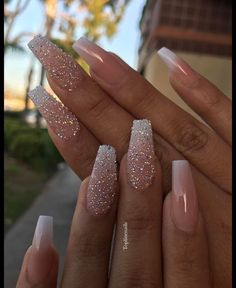 someone is holding their nails with some glitter on them, and there are two fingers in the foreground