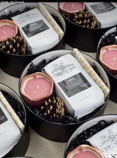 several candles are arranged in black trays with pine cones