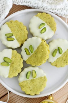 some cookies with white frosting and pistachios on a plate next to a christmas ornament