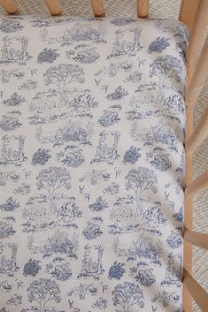 a blue and white toiler print pillow on top of a wooden crib