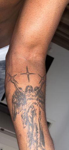 a man with a cross and angel tattoo on his arm