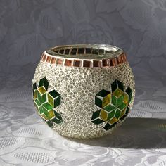 a silver and green vase sitting on top of a white tablecloth covered table cloth