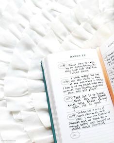 an open book with writing on it sitting next to a pile of white paper sheets