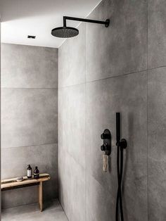 a bathroom with a walk in shower next to a bench and wall mounted faucet