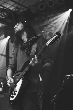 a man with long hair playing an electric guitar at a music festival in black and white