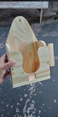 a person holding a wooden toy boat on top of a cement floor next to a bench