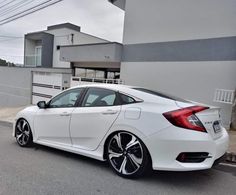 a white car parked in front of a building on the side of a road with black rims