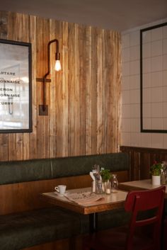 a restaurant with wood paneling and green booths, two red chairs at the table