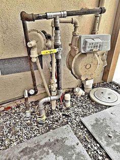 an old water heater and pipes are on the ground next to a building wall