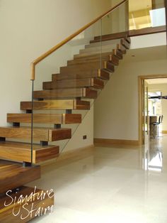 a wooden stair case with glass balustncing and wood handrails in a house