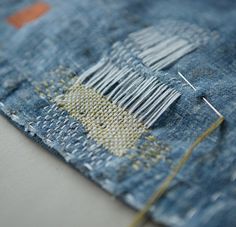 a piece of denim with some pins sticking out of it