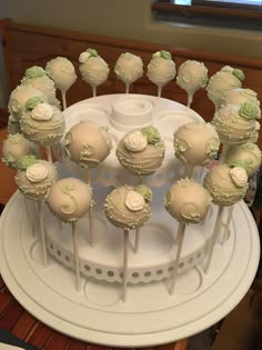 there is a cake with white frosting and green decorations on the top, surrounded by cupcakes