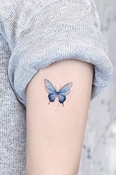 a small blue butterfly tattoo on the left inner side of the right arm and shoulder