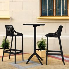 two chairs and a table sitting on the side of a building next to each other