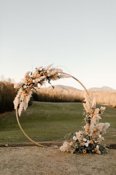 a wedding arch decorated with flowers and pamodia in front of a golf course