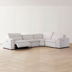 a white sectional sofa sitting on top of a hard wood floor next to a wall