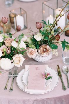 the table is set with white and pink flowers, silverware, and napkins