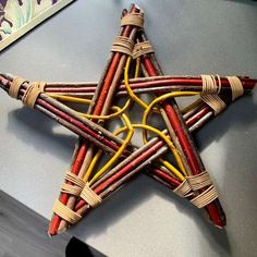 an ornament made out of sticks and colored yarn is displayed on a table