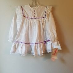 "- This lovely vintage dress by Beautique is ready to be worn! It is white with long sleeves and buttons at back of neck. There is a textured stripe in white as well on fabric. The yoke is trimmed in purple ribbon with white lace ruffles that are mimicked at the hem. There is white lace trimming the bottom of hemline as well. This dress sold new at PixieLand in Michigan. Size: 2t Length: 17.5\"	in stock	38.25 USD	"	0.00 USD	Clothing > Girls' Clothing > Dresses
https://i.etsystatic.com/6769639/r/ White Button-up Dress For Dress-up Occasion, White Long Sleeve Prairie Dress, White Dress With Buttons For Dress-up, Cute White Vintage Dress With Lace Trim, Cute Fitted Vintage Long Sleeve Dress, Cute Fitted Vintage Dress With Long Sleeves, Cute Fitted Long Sleeve Vintage Dress, Cute White Dresses With Buttons, Fitted Long Sleeve Vintage Dress, Cute Style