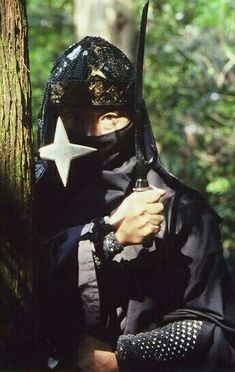 a person wearing a mask and holding a star in their hand while standing next to a tree