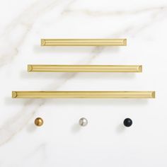 brass handles and knobs on a white marble countertop with gold, black, and silver balls