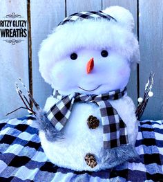 a snowman is sitting on top of a checkered tablecloth and wearing a hat