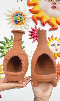 two clay vases are being held by someone's hand