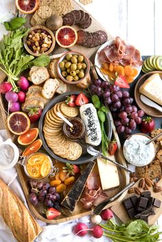 an assortment of cheeses, crackers, fruits and meats on a platter