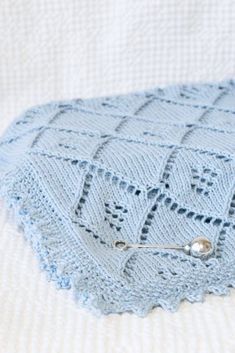 a crocheted blue blanket on top of a bed with a pin in it