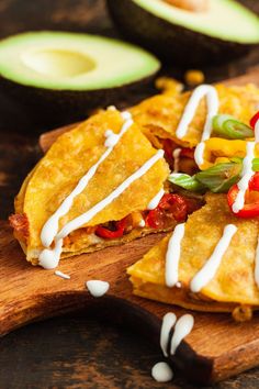 some tortillas are sitting on a cutting board with avocado slices around them