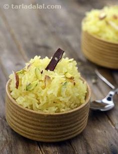 two small wooden bowls filled with rice on top of a wooden table next to spoons