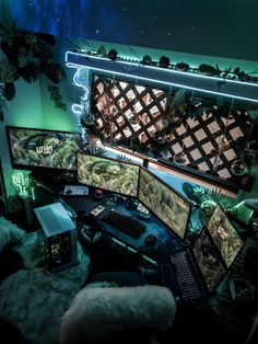 a computer desk topped with three monitors and a laptop next to a wall covered in plants