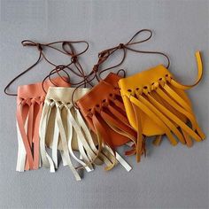 four pairs of leather gloves hanging on a wall with cords attached to them, all in different colors