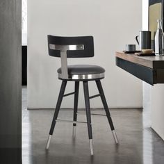 a black and silver bar stool in front of a desk with a coffee cup on it