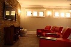 a living room filled with red chairs and a flat screen tv mounted to the wall