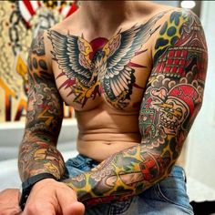 a man with lots of tattoos on his chest and arms, sitting in front of a mirror