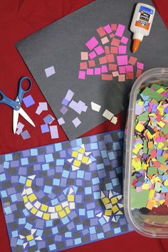 some crafting supplies are laying out on a red tablecloth with scissors and paper