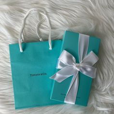 a tiffany & co gift bag with a white bow on it and a blue box that says tiffany & co