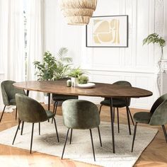 a dining room table with green chairs and a white rug on the floor in front of it